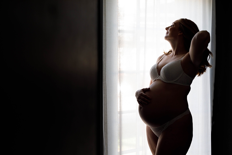 silhouette of a pregnant woman in a window sharing hair
