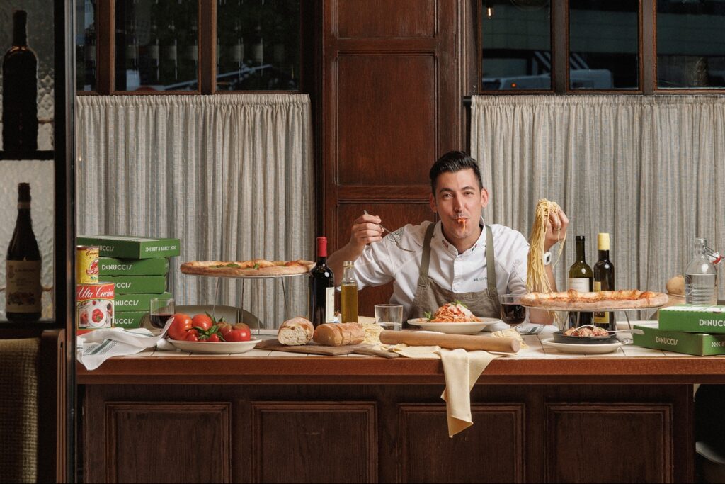 Photo of Chef Sal of Ballyhoo restaurant group holding pasta and eating for the scout guide