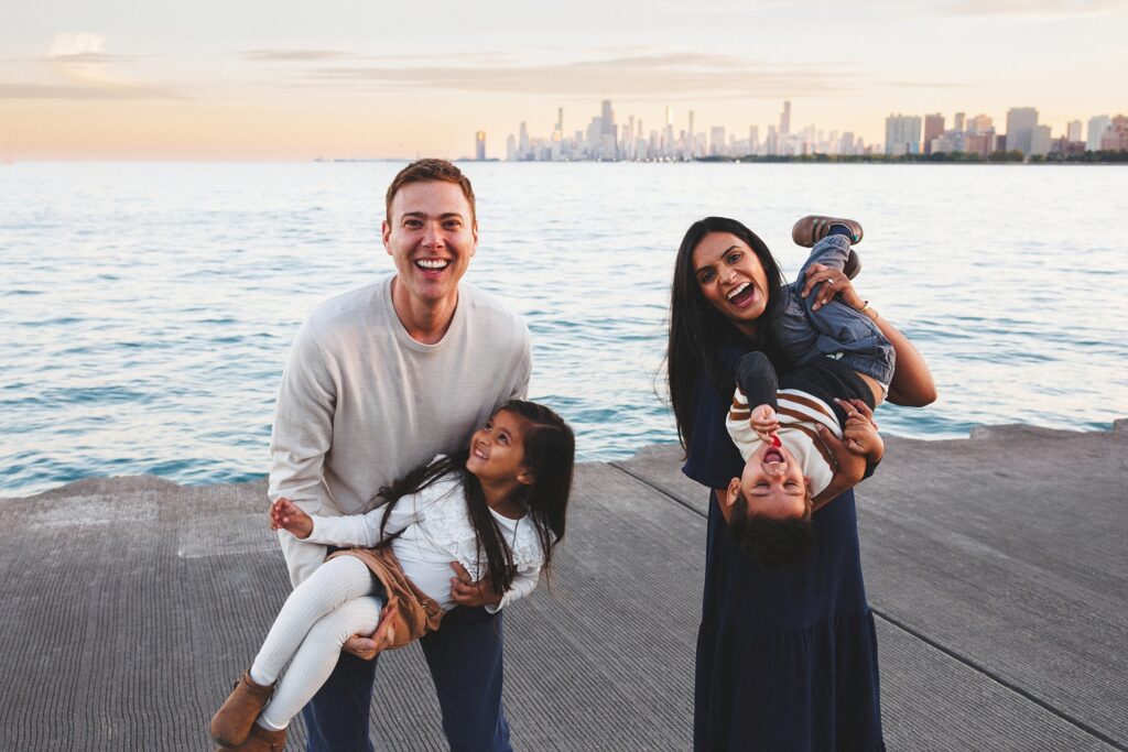 Backlit sunset family portrait in at Montrose Harbor in Chicago with warm glow and playful movement
