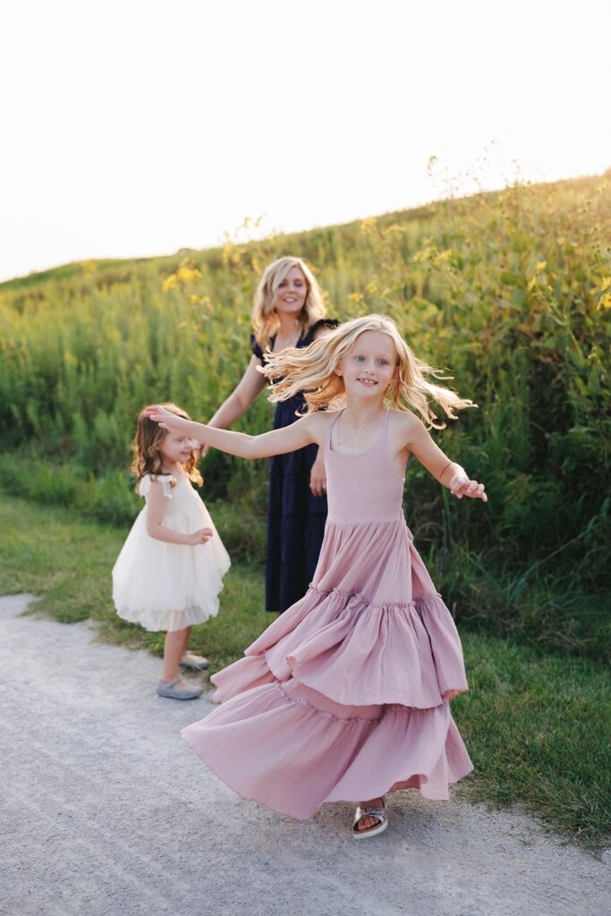 a mom and her daughters dance in a field together