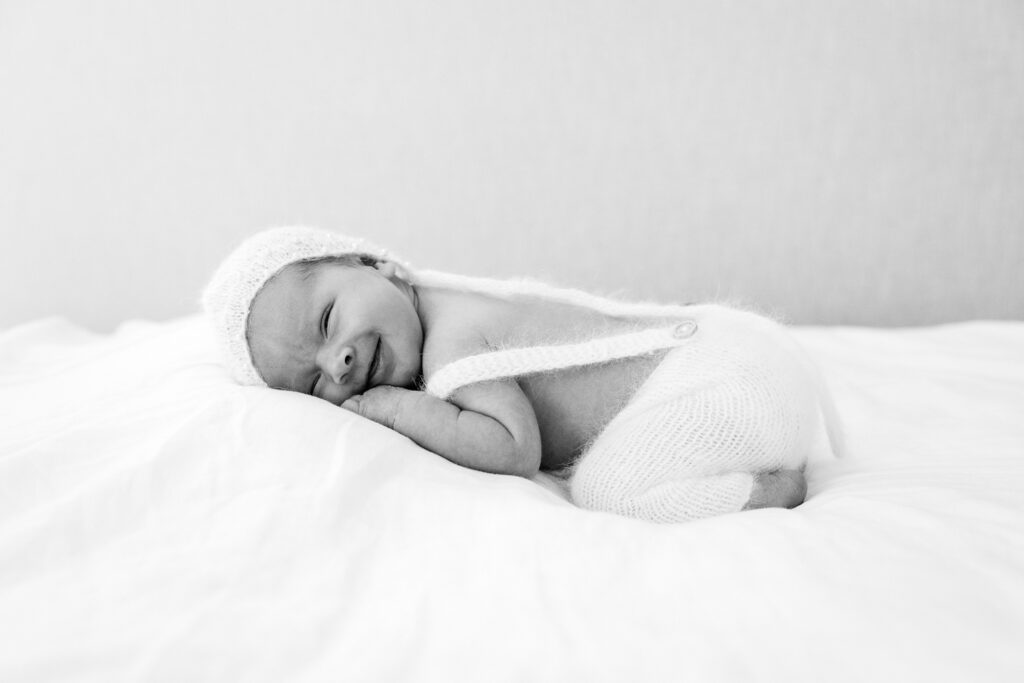 a newborn baby in a white outfit poses on a pillow during it's first photoshoot