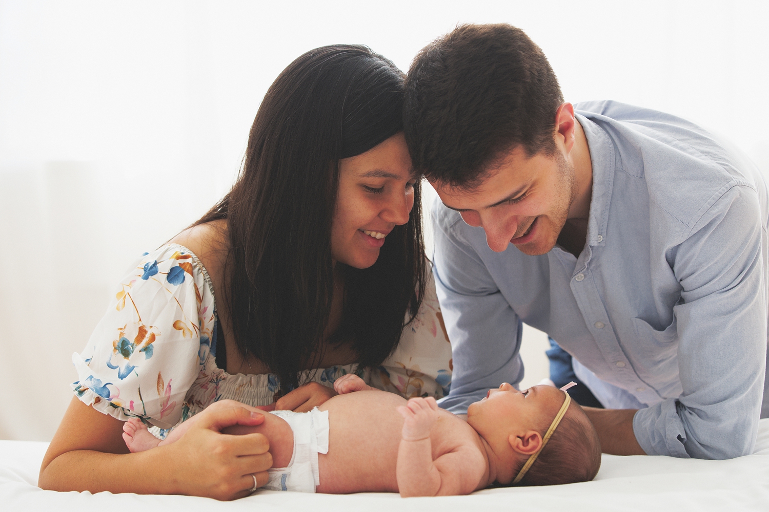a mom and son look on adoringly at their newborn baby