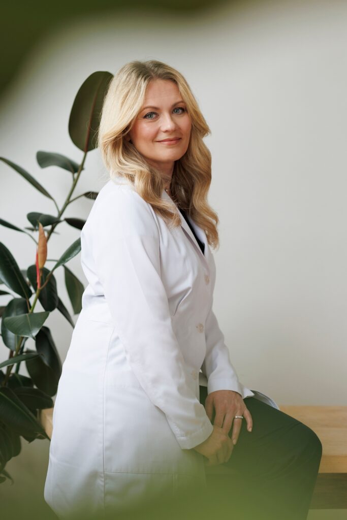 a doctor poses on a table in a white lab coat