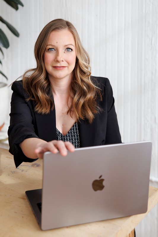 a criminal defense attorney poses with her computer for branding photos in a chicago photo studio