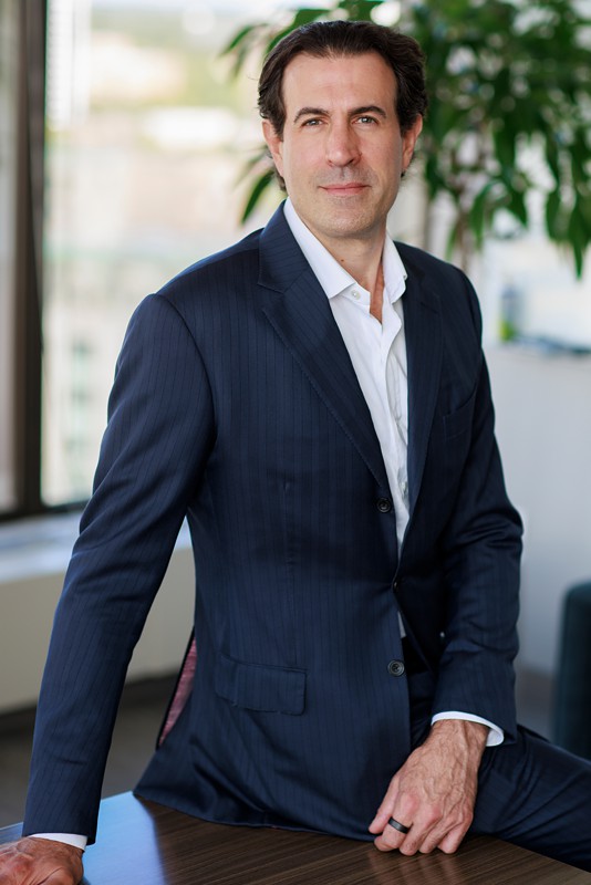 a man poses for a corporate portrait in a blue suit