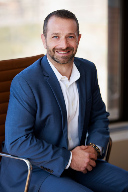 a man poses for a corporate portrait in a blue suit