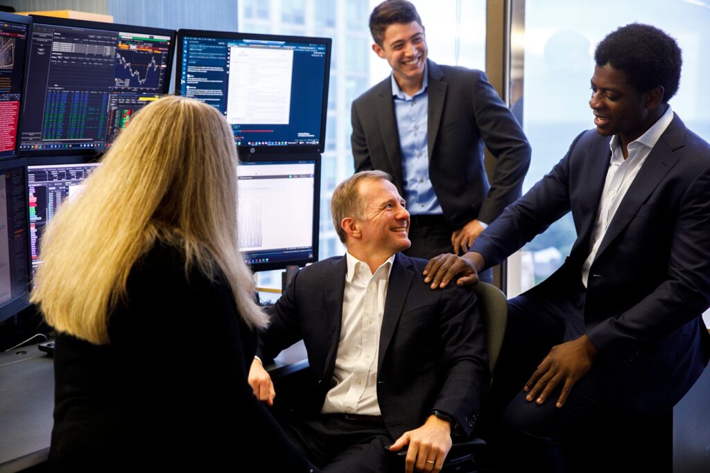 a group of traders talk together over a computer