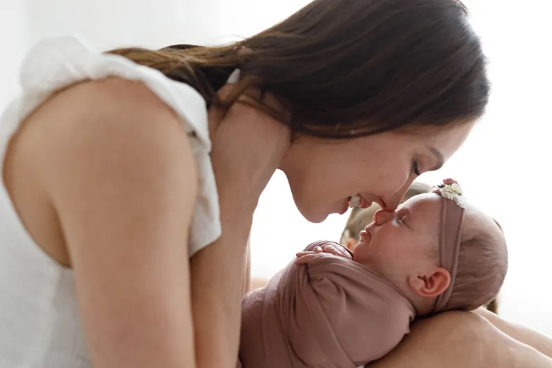 a mother goes nose to nose with her daughter in her newborn photos at home