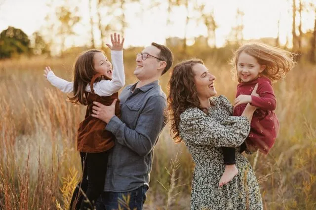 a mother and father play with their two daughters in a field at montrose harbor in chicago