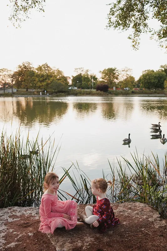 two sisters sit together near a pond at Humboldt park in chicago, IL