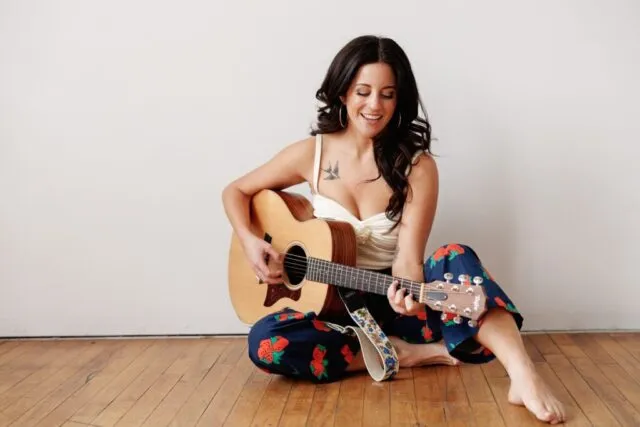 a woman playing a guitar during her portrait photoshoot in a chicago studio