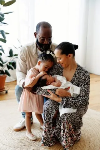 group photo of mom holding a newborn with her daughter snuggling and her husband also hugging them at Rife Ponce Photography a chicago photo studio