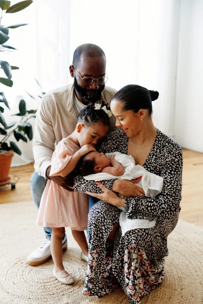 group photo of mom holding a newborn with her daughter snuggling and her husband also hugging them at Rife Ponce Photography a chicago photo studio