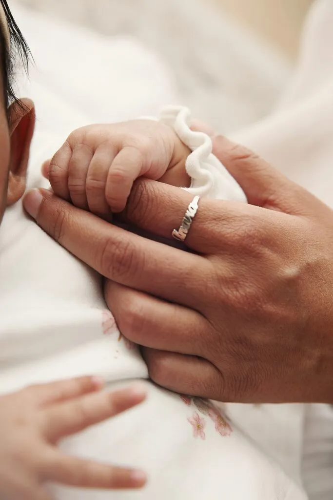 a detail photo of a mom holding the hand of her newborn baby