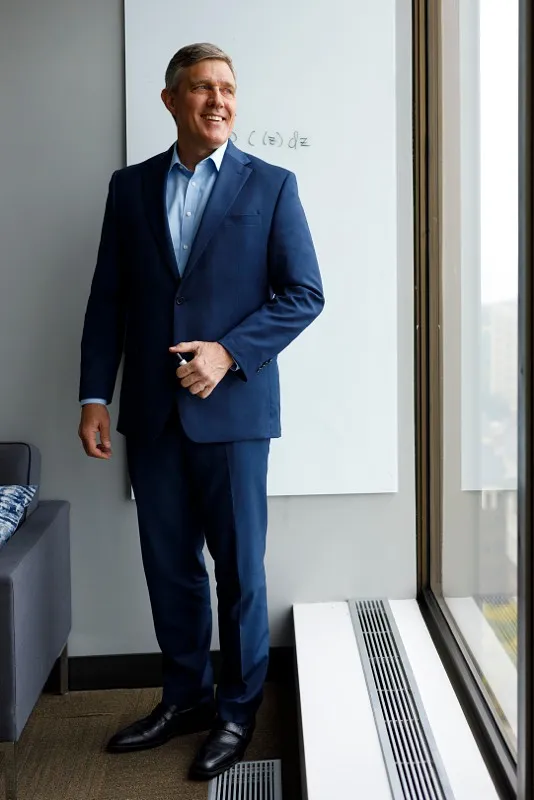 man looking out window of a corporate building