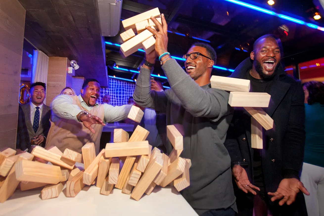 guests at a birthday party react to a large jenga puzzle collapsing